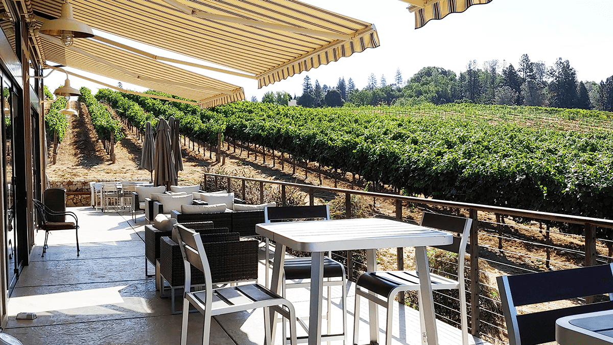 Outside table seating with awning looking over vineyard.